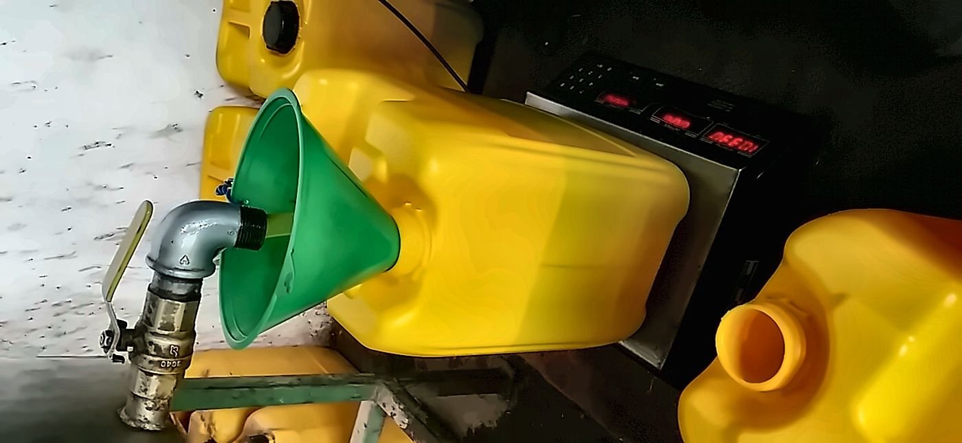 Fresh oil being poured through a green funnel into yellow containers